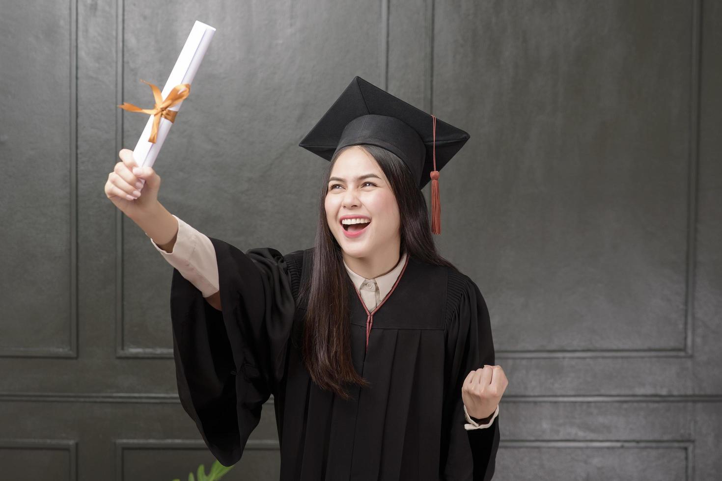 retrato de mujer joven en bata de graduación sonriendo y animando sobre fondo negro foto