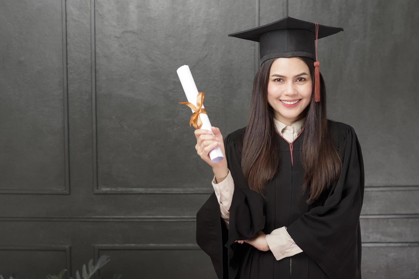 Portrait of young woman in graduation gown smiling and cheering on