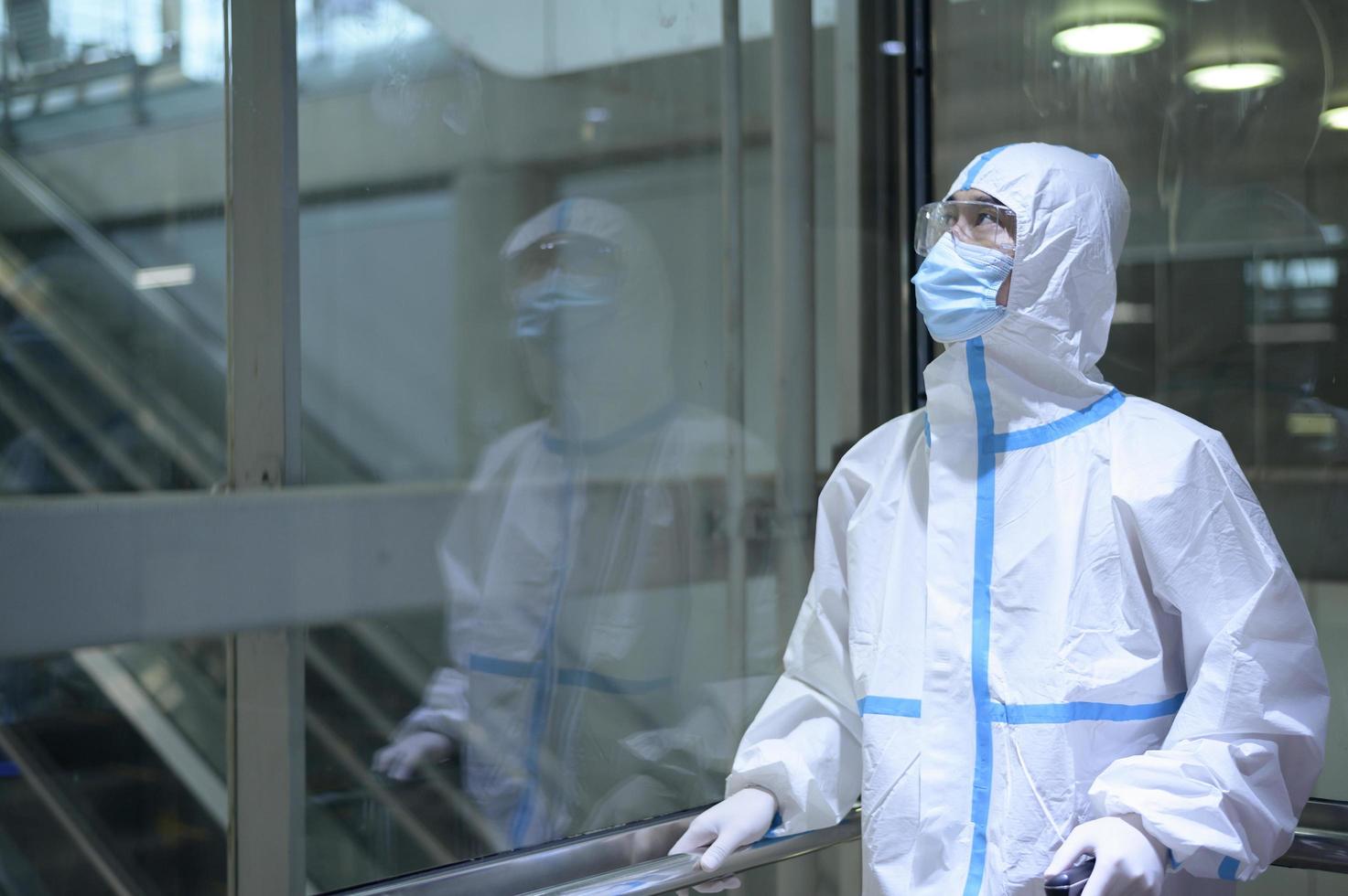 An Asian man is wearing ppe suit in airport elevator , Safety travel , covid-19 protection , social distancing concept photo