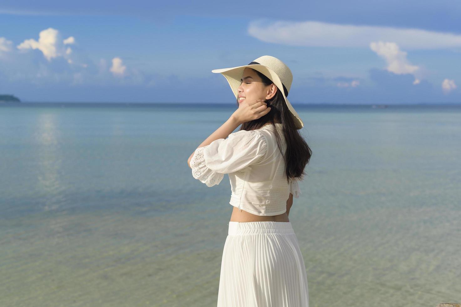 A happy beautiful woman in white dress enjoying and relaxing on the beach, Summer and holidays concept photo