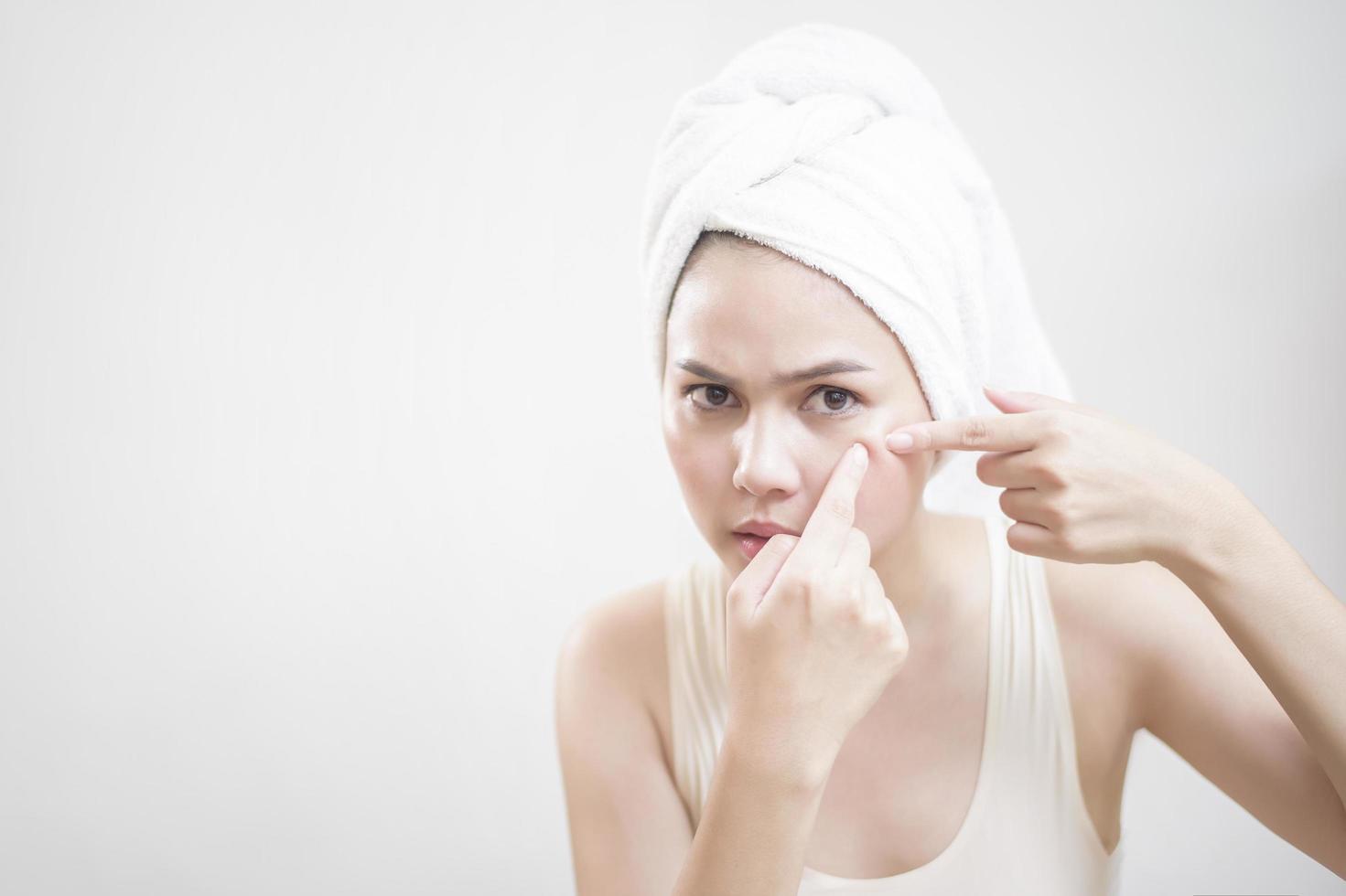 A woman is popping a pimple photo