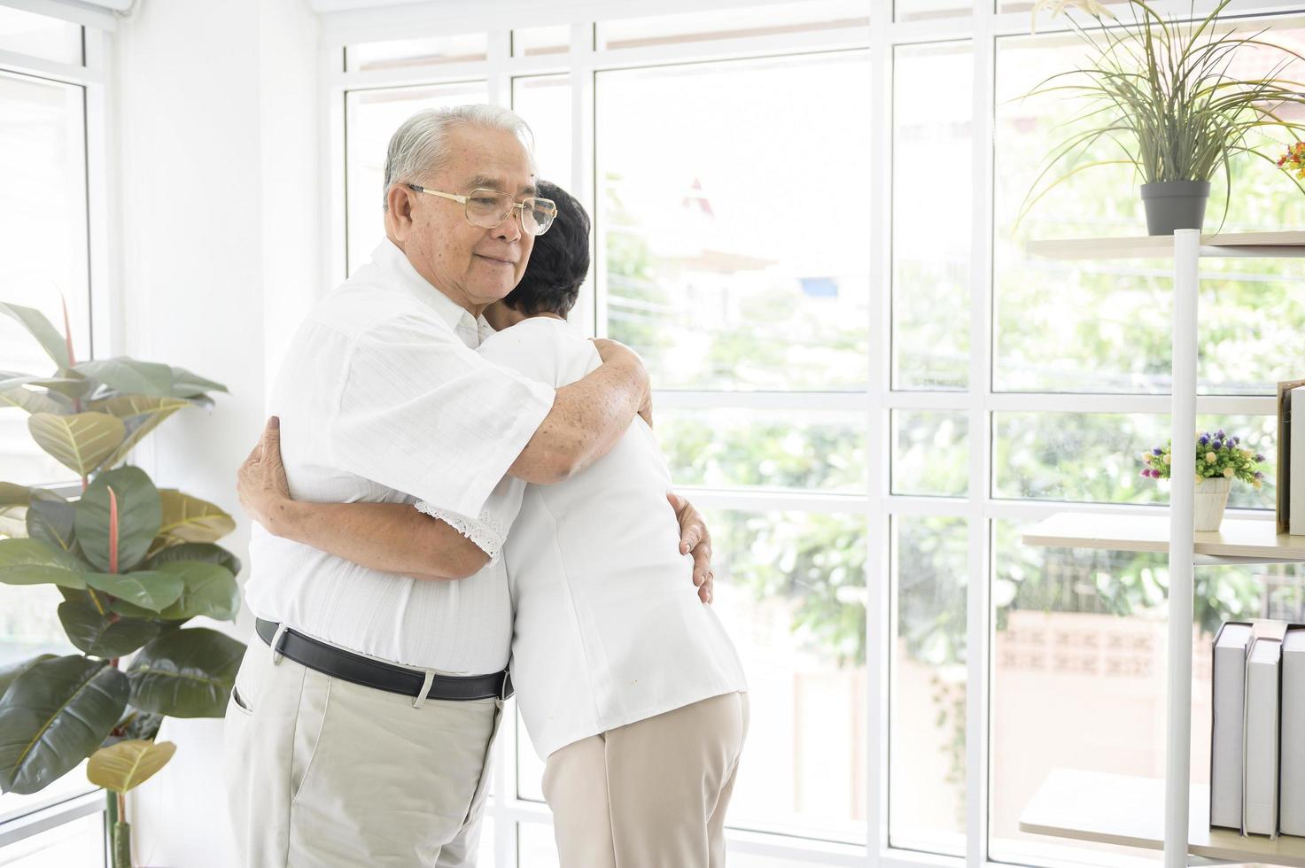 A senior elderly couple are hugging in home photo