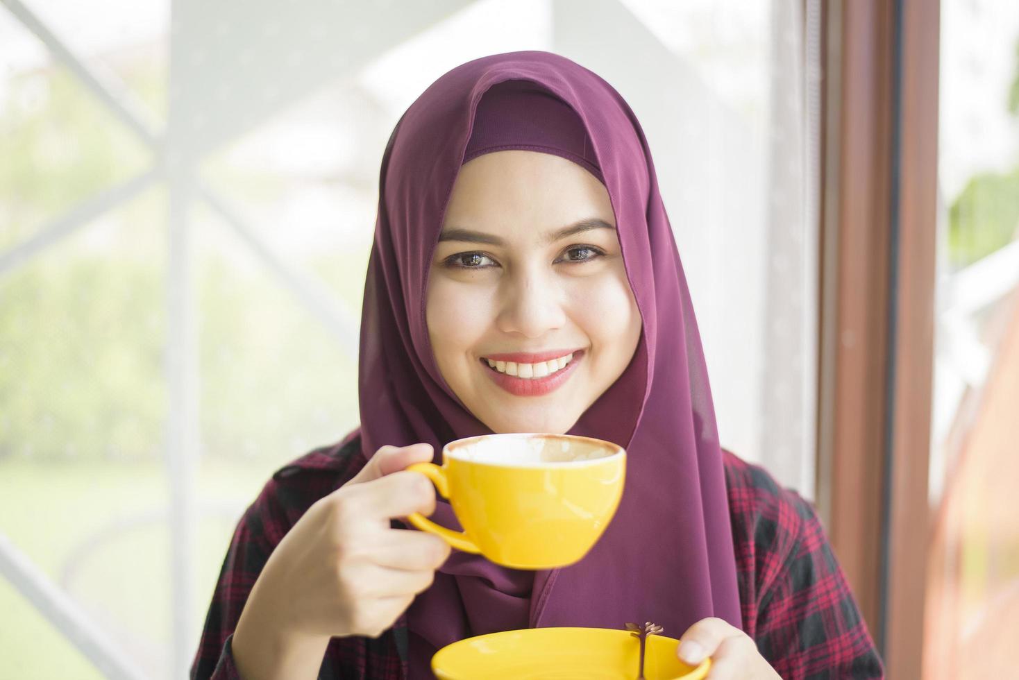 Muslim woman with hijab is working with laptop computer in coffee shop photo