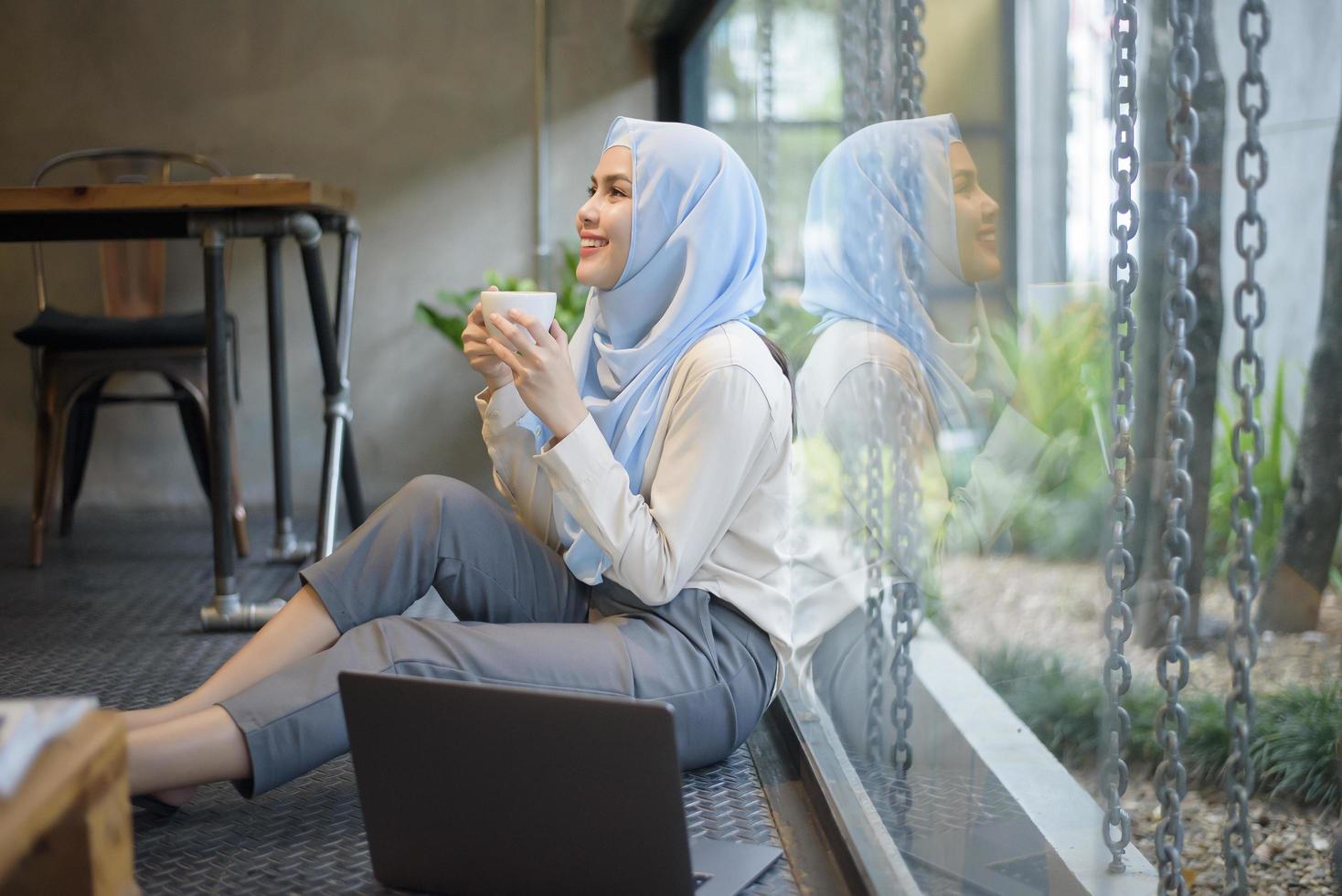 Muslim woman with hijab is working with laptop computer in coffee shop photo