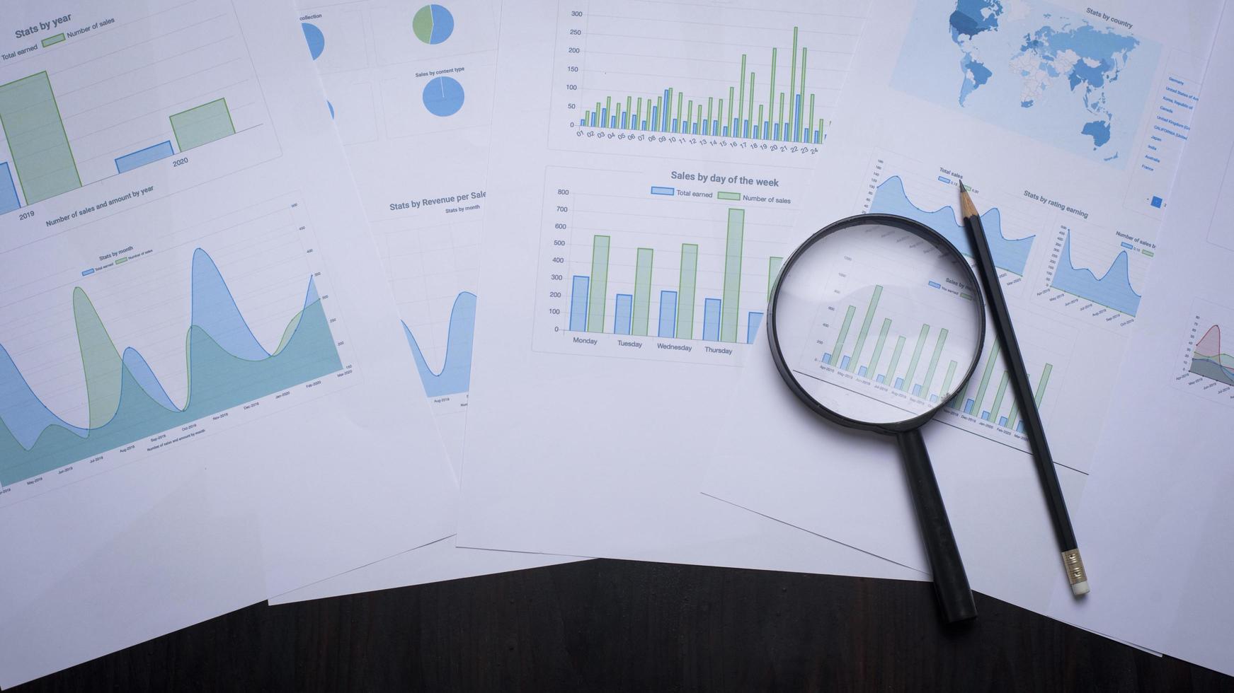 Magnifying glass and documents with analytics data lying on table photo