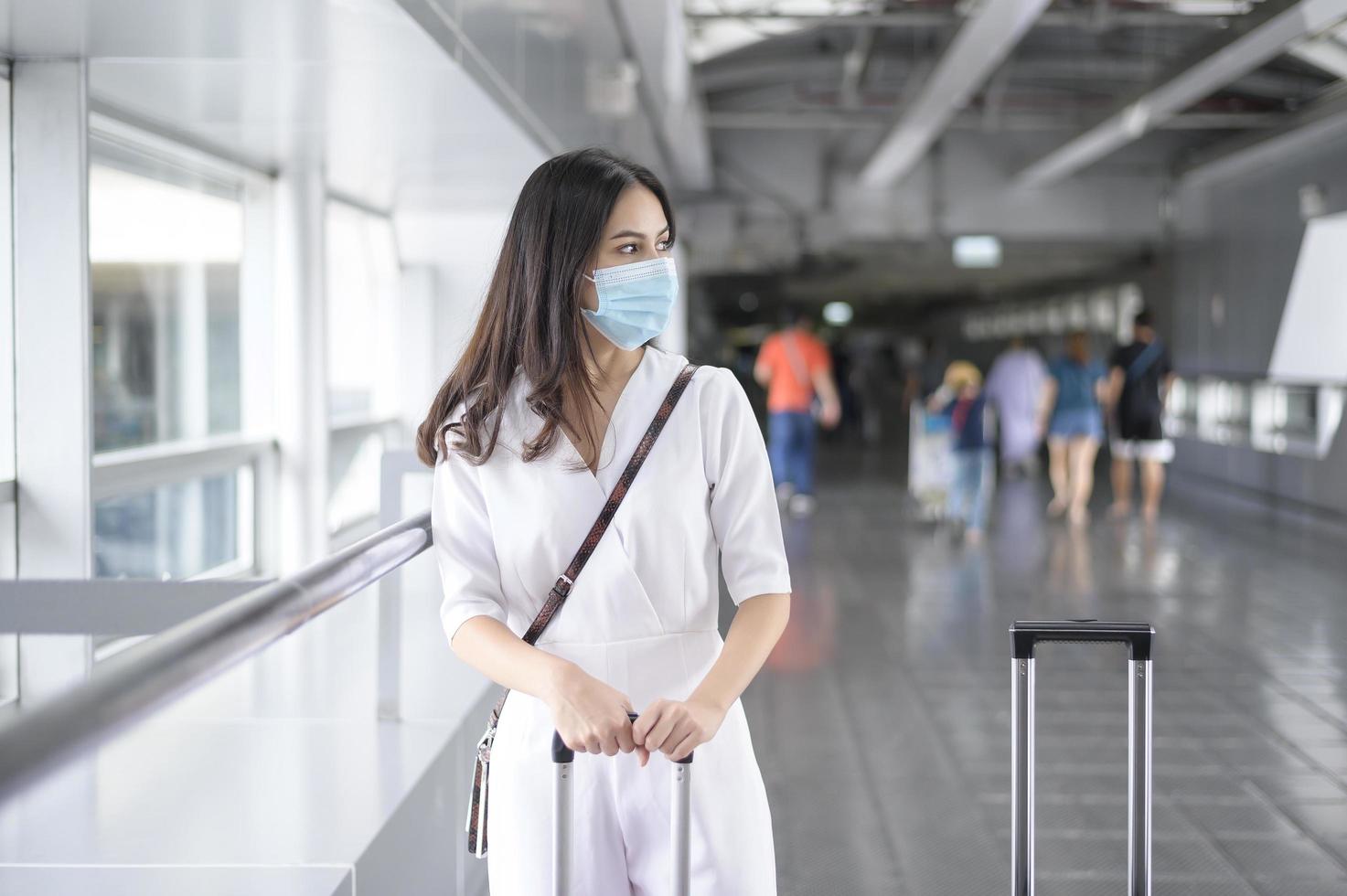 una mujer viajera lleva una máscara protectora en el aeropuerto internacional, viaja bajo la pandemia de covid-19, viajes de seguridad, protocolo de distanciamiento social, nuevo concepto de viaje normal foto