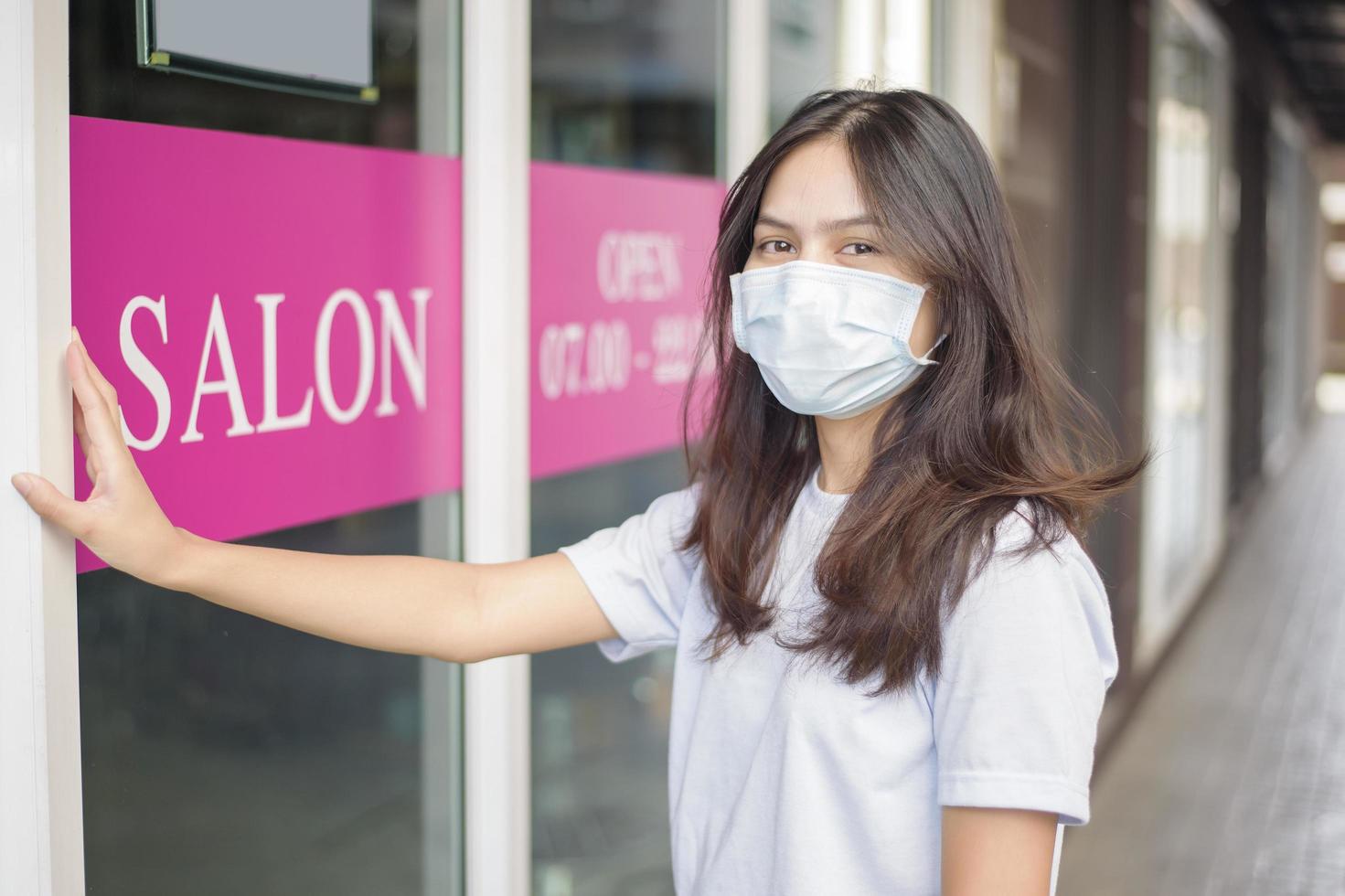 a young woman is wearing face mask for protection covid-19 standing in front of Salon shop, salon safety concept photo