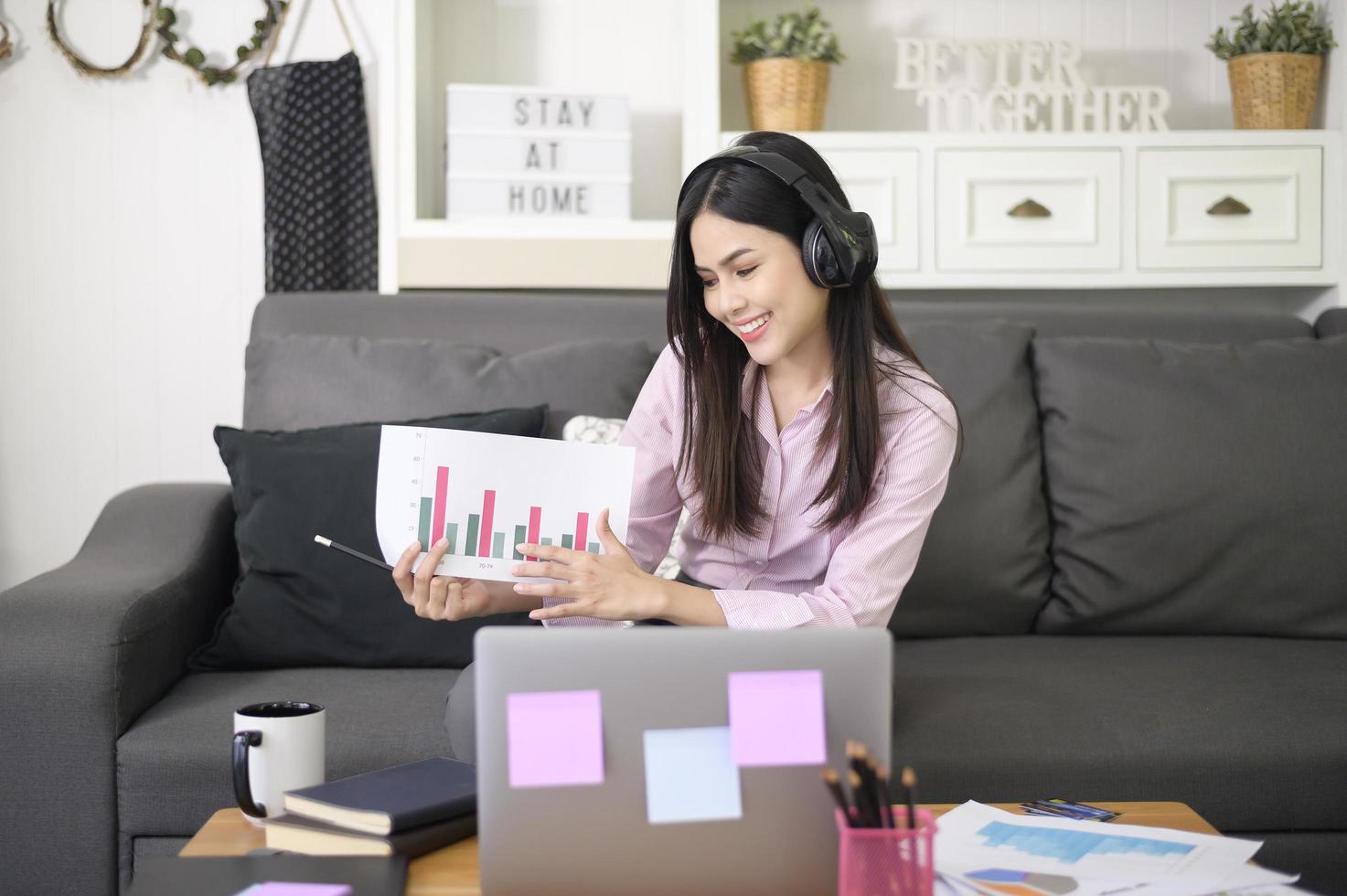 una hermosa joven que usa auriculares está haciendo una videoconferencia a través de una computadora en casa, concepto de tecnología empresarial. foto