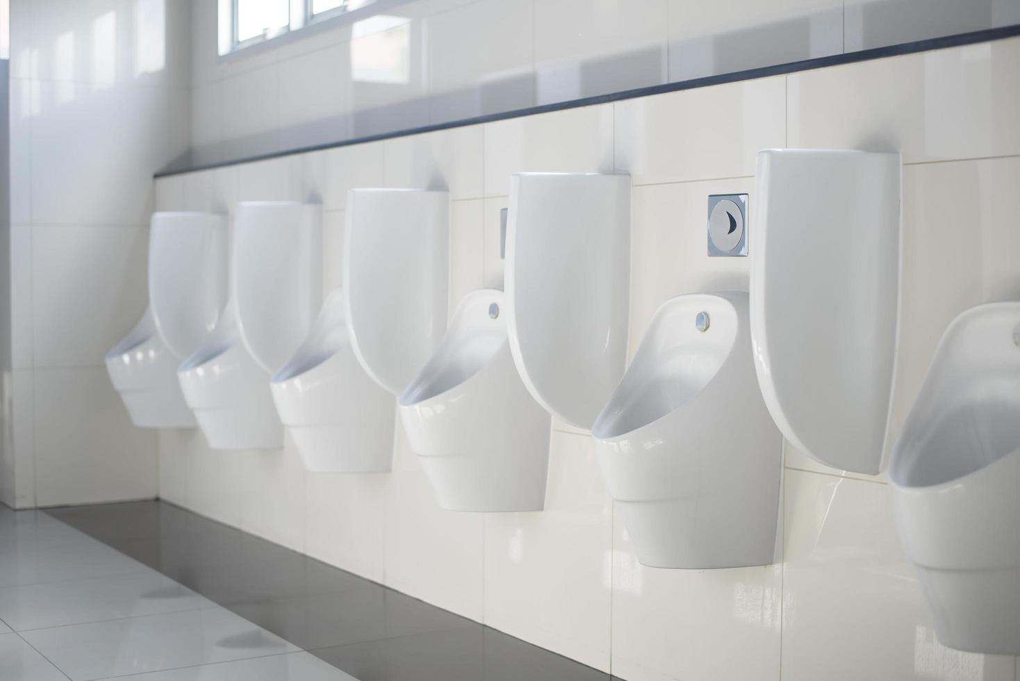 Row of white ceramic urinals for men in restroom. photo