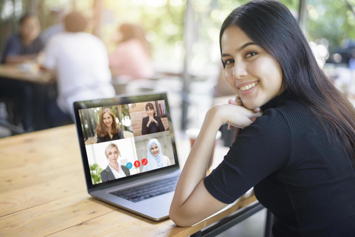 una joven está mirando la pantalla de su computadora mientras se encuentra en una reunión de negocios a través de una aplicación de videoconferencia foto