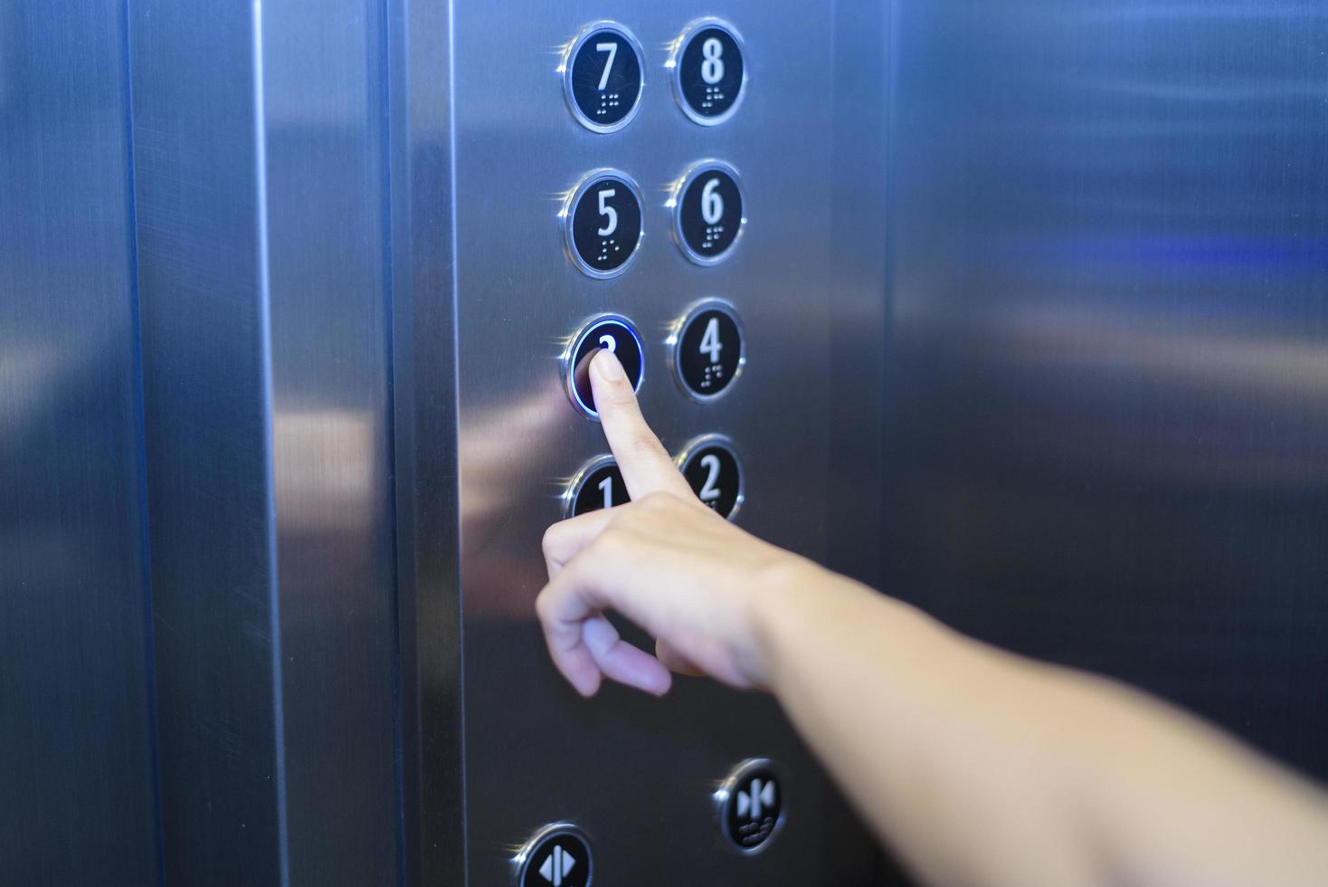 el primer plano del dedo humano está presionando el botón del elevador foto