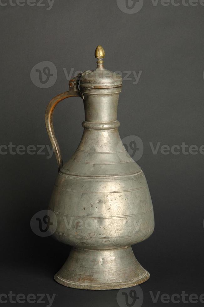 ancient oriental metal jug on dark background. antique bronze tableware photo