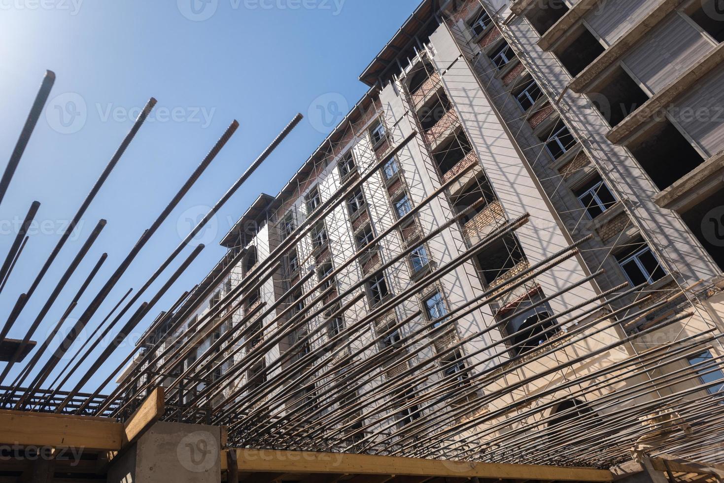 reinforcement bars for concrete pouring on the background of the building under construction. close-up, bottom view photo