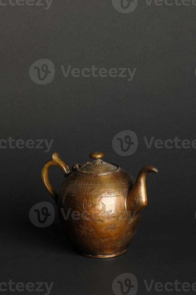 ancient oriental metal teapot on dark background. antique bronze tableware photo