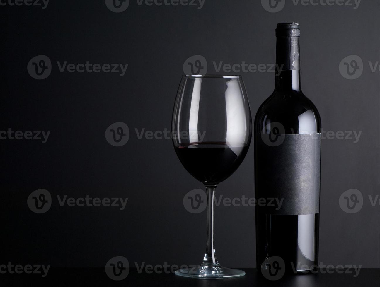 bottle red of wine with a glass on a black background photo