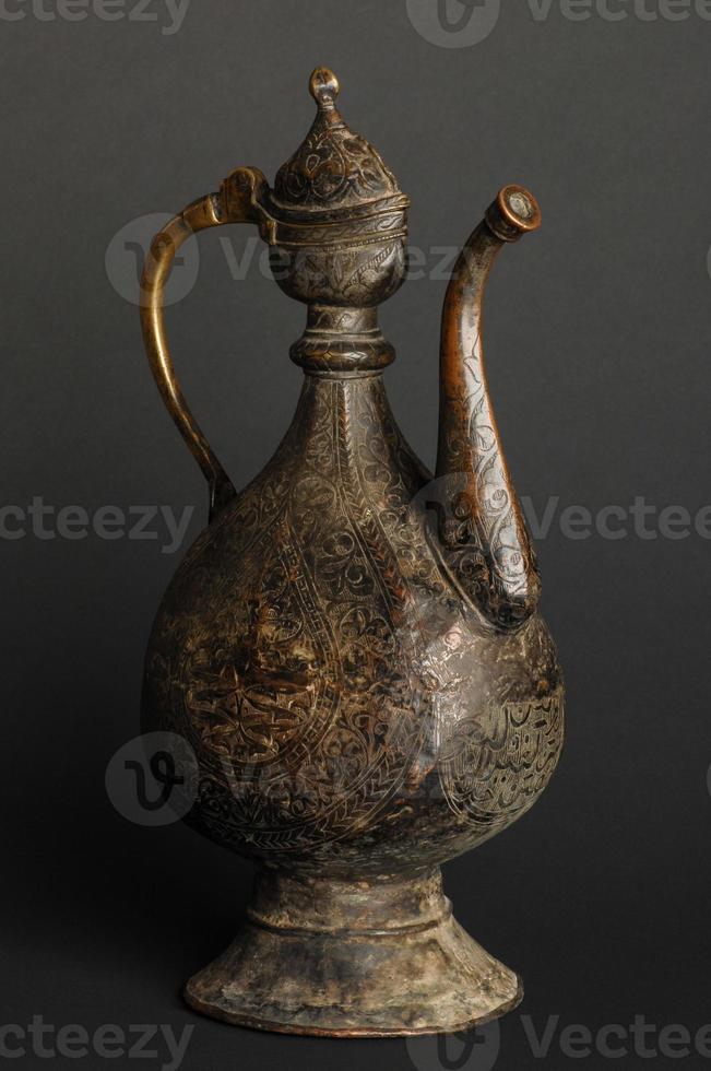 ancient oriental metal teapot on dark background. antique bronze tableware photo