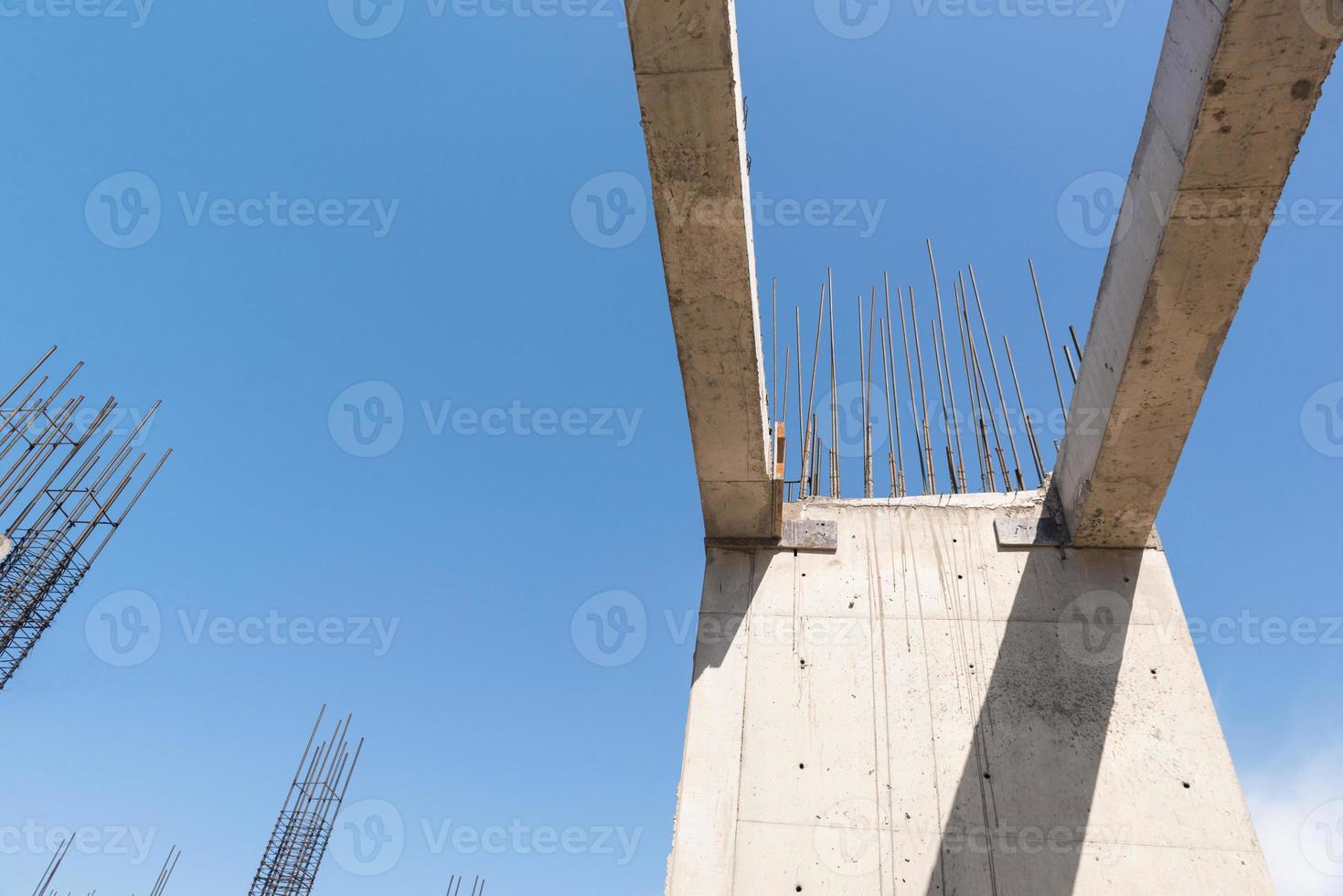 concrete walls and columns in the in the building under construction, in a blue sky background. bottom view photo