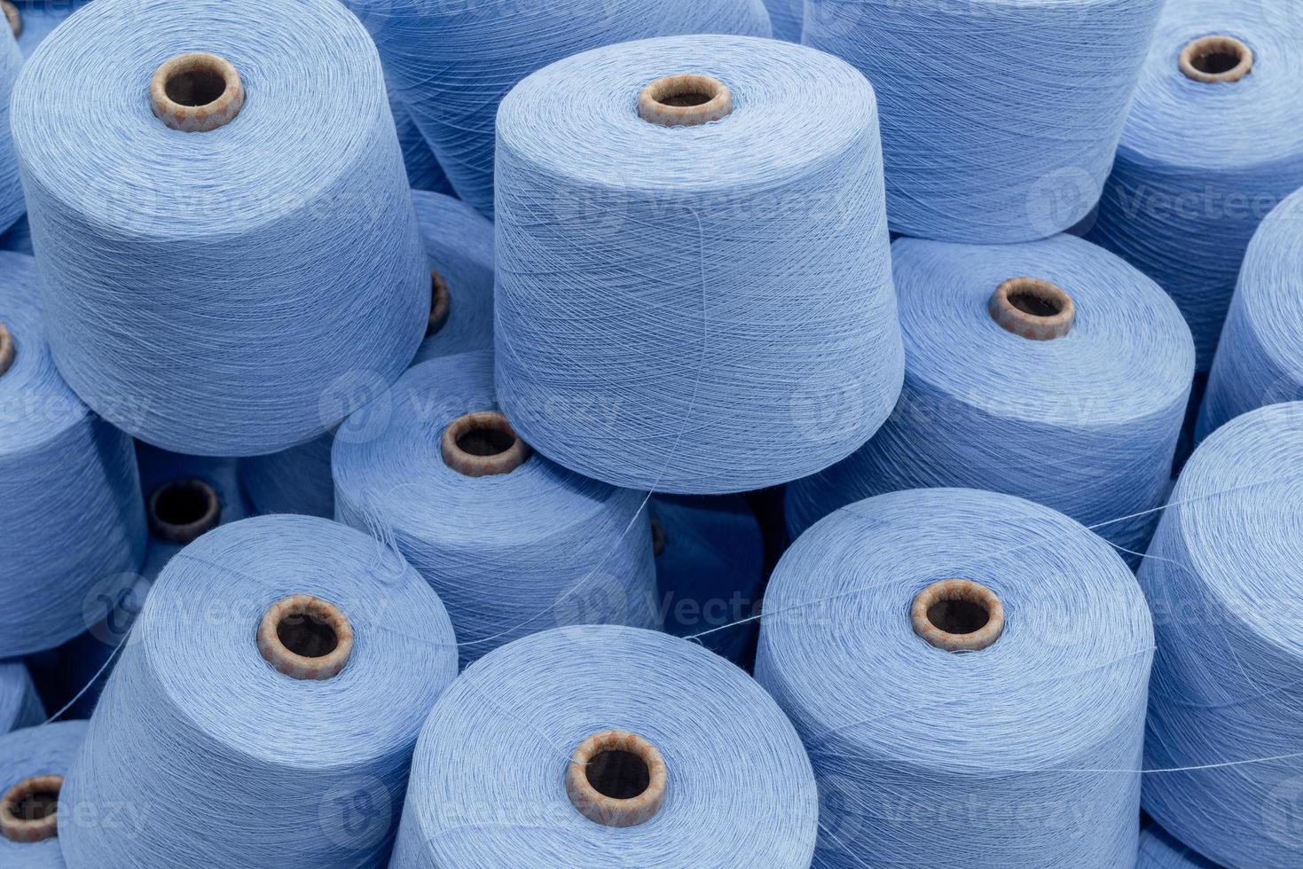 large pile of spools of blue thread. closeup photo