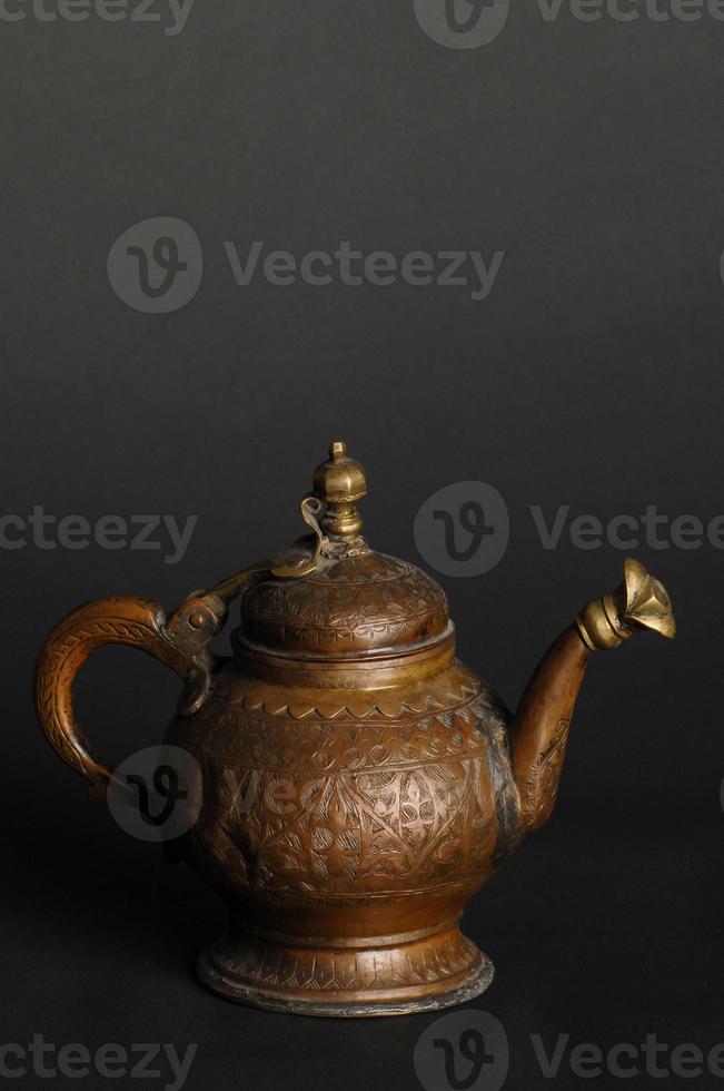 ancient oriental metal teapot on dark background. antique bronze tableware photo