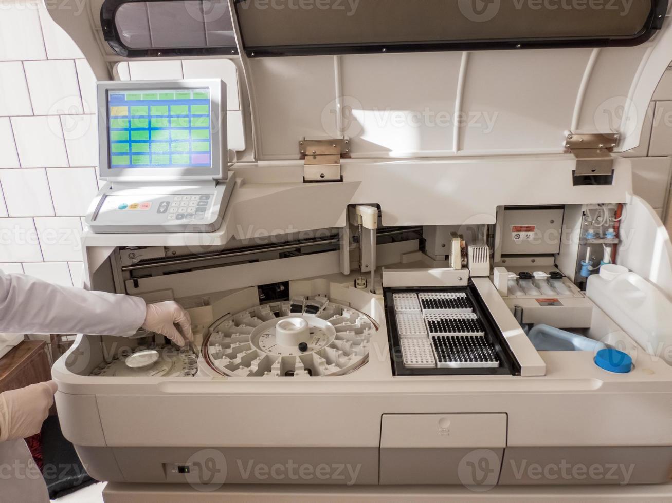 girl in the lab puts the serum samples in a medical device for analysis. Machine automatic biochemical analysis photo