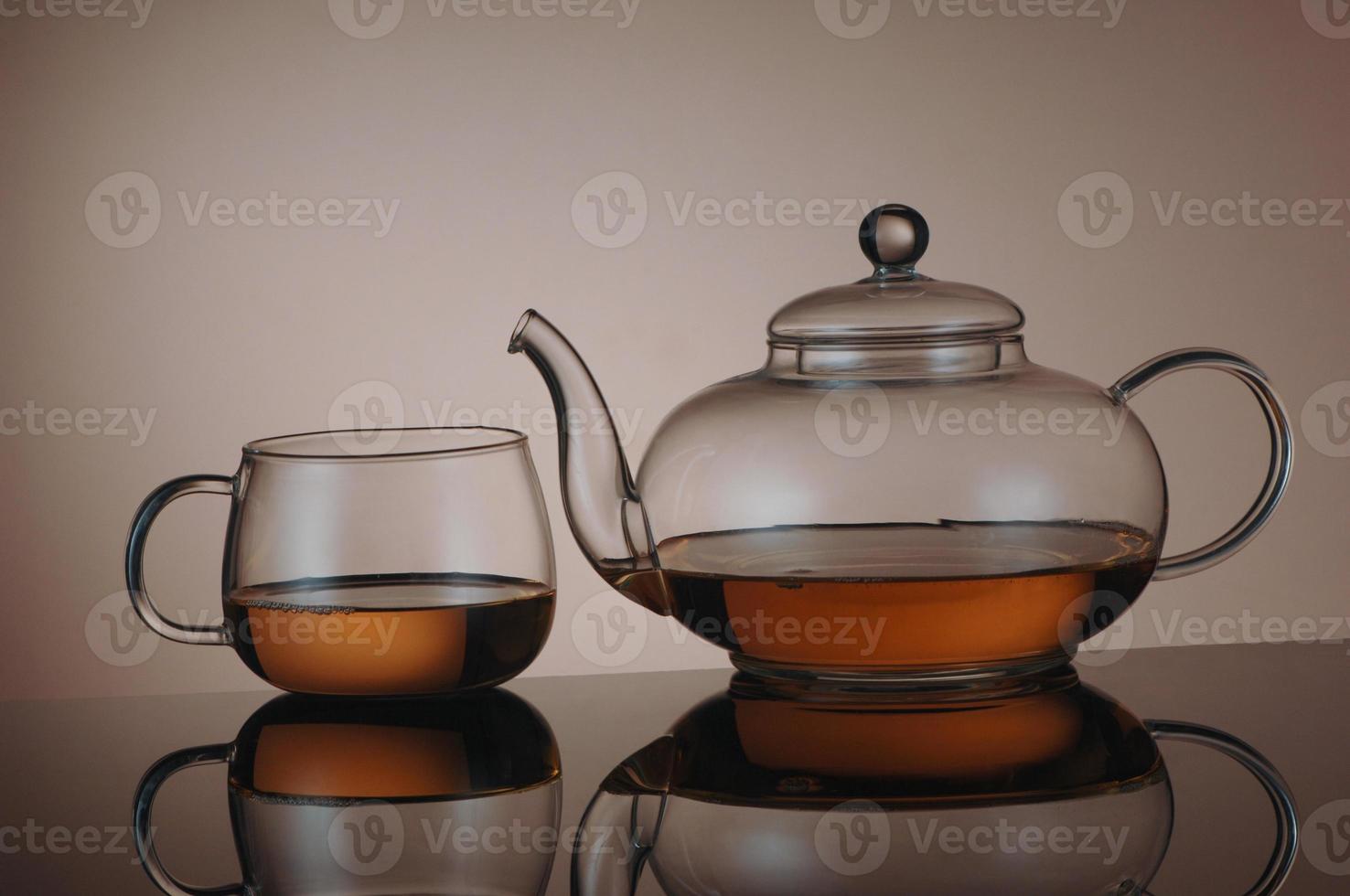 tetera de vidrio transparente y taza de té con reflejo foto