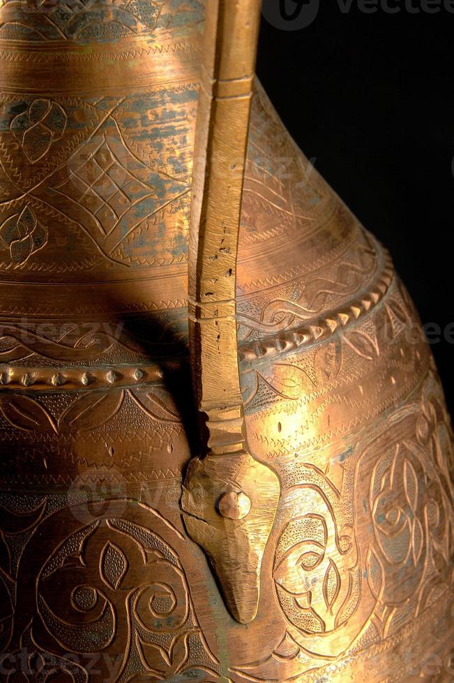 Part ancient oriental metal jug on dark background. Antique bronze tableware photo