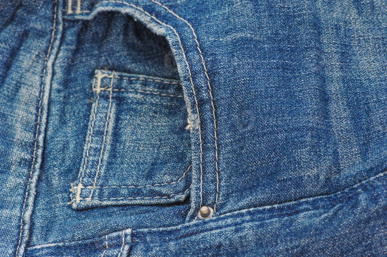 part of the blue denim pants with pockets and rivets, closeup photo