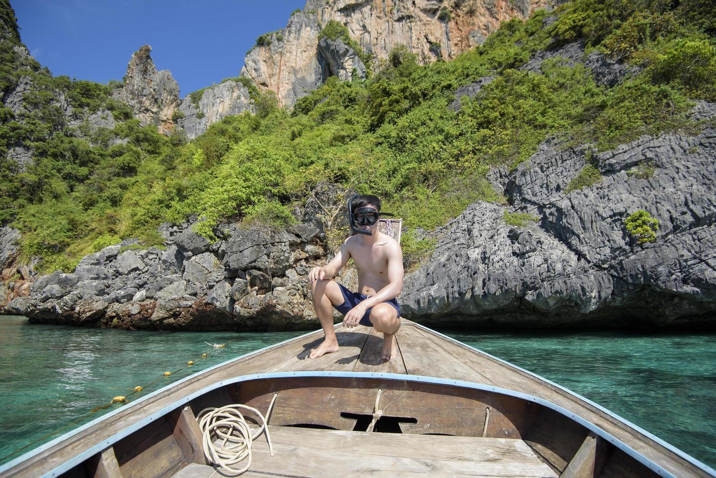 An active man on thai traditional longtail Boat is ready to snorkel and dive, Phi phi Islands, Thailand photo