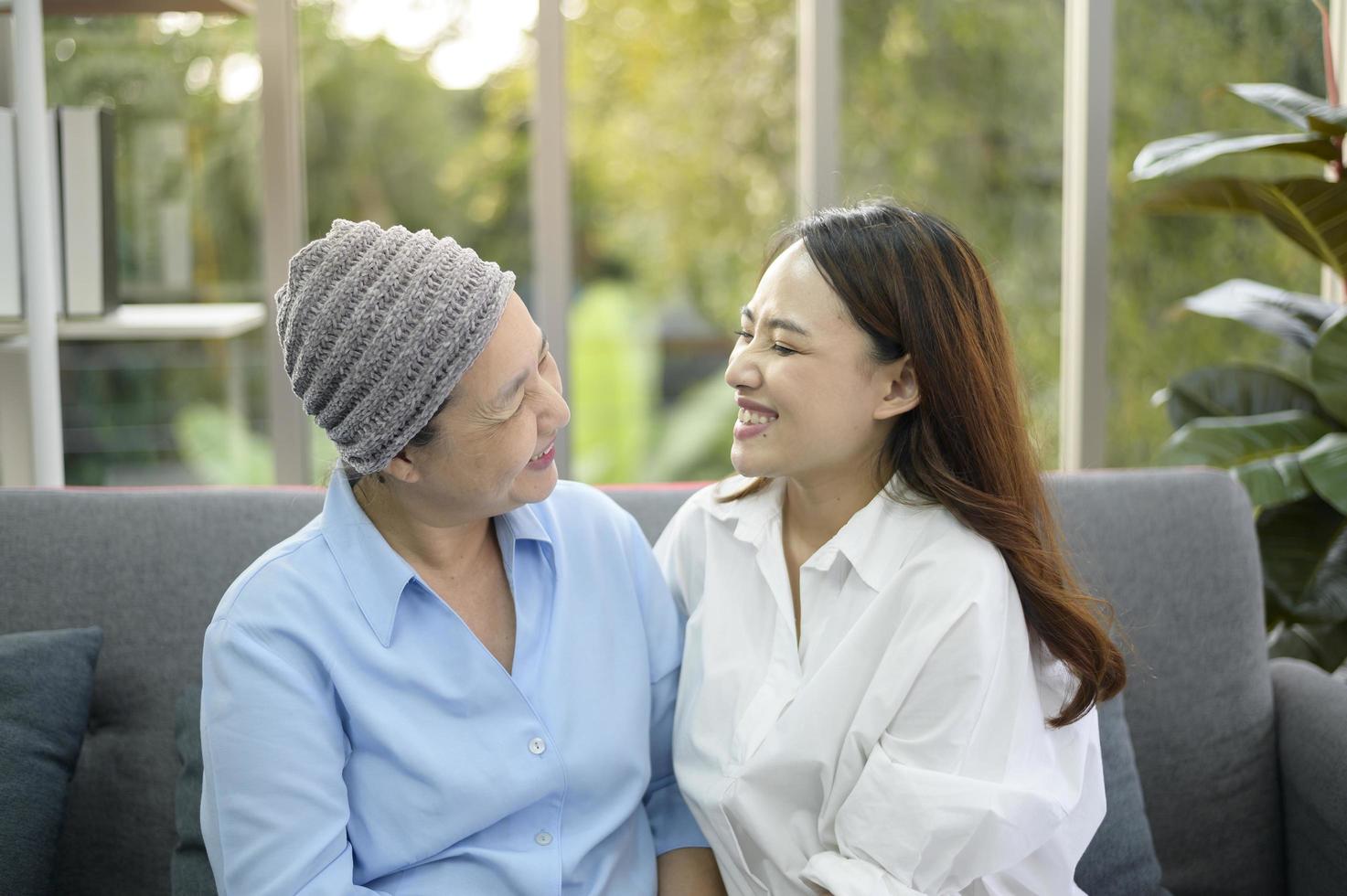 Cancer patient woman wearing head scarf hugging her supportive daughter indoors, health and insurance concept. photo