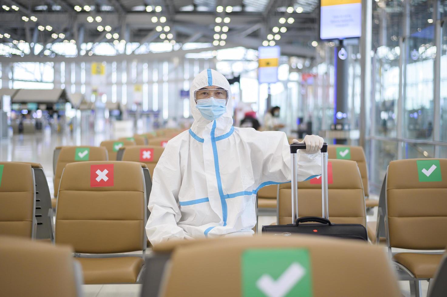 un hombre asiático lleva traje de ppe en el aeropuerto internacional, viajes de seguridad, protección covid-19, concepto de distanciamiento social foto