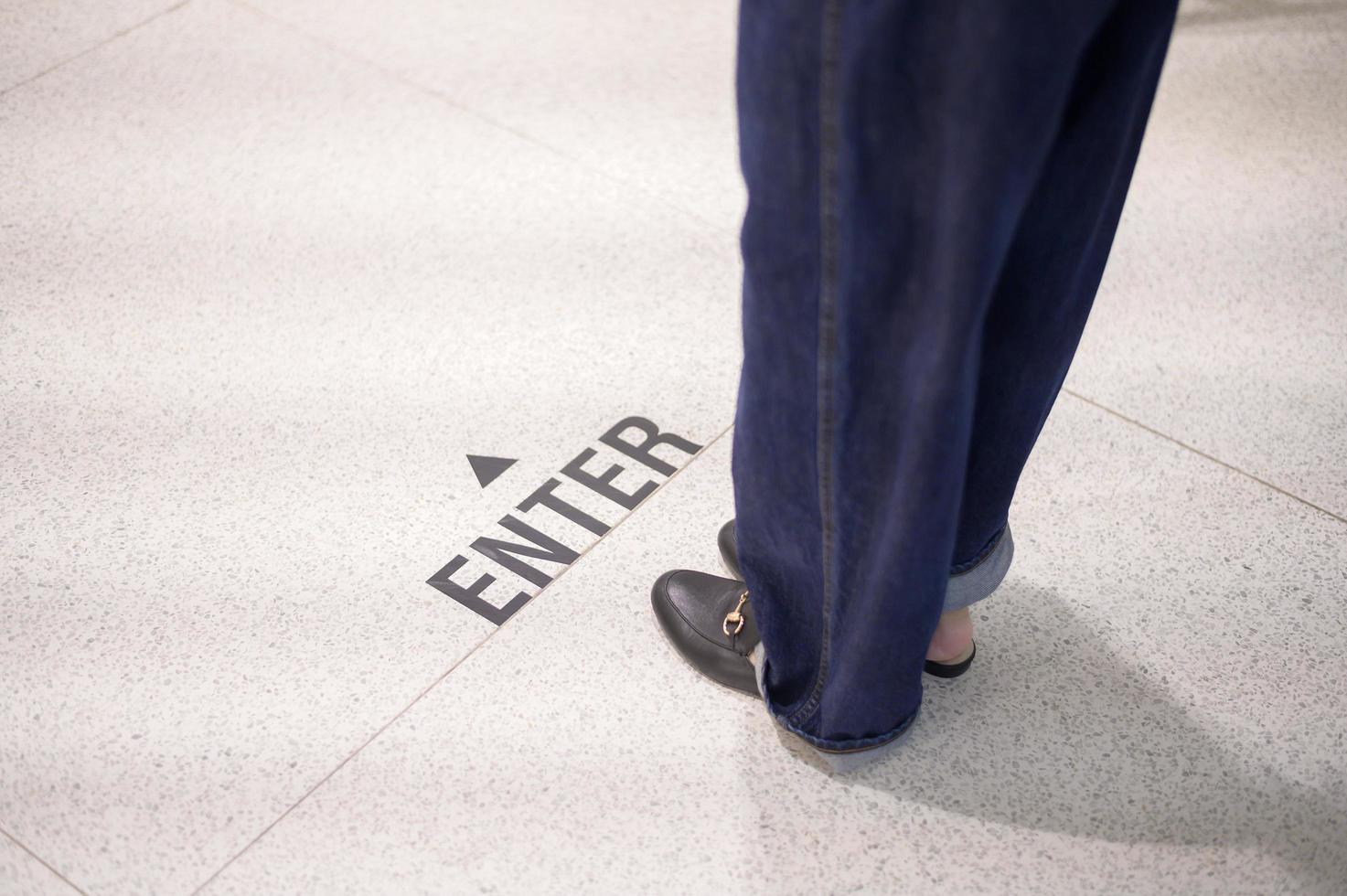 cerrar las piernas de la mujer está de pie en la línea de distanciamiento social en el centro comercial, nueva normalidad, distanciamiento social, concepto de prevención covid-19 foto