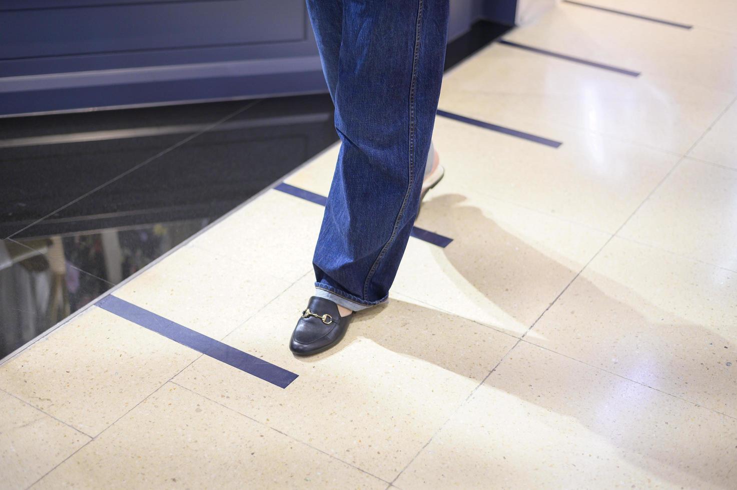 Close up woman legs is standing on social distancing line in shopping mall , New normal , social distancing, covid-19 prevention concept photo