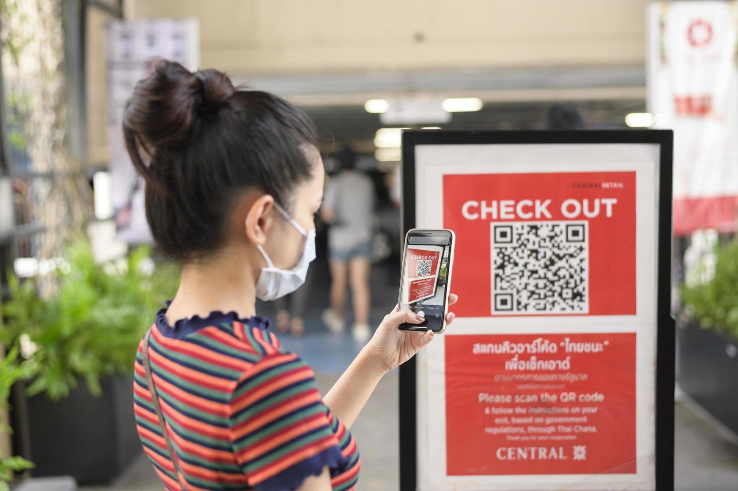 la mano de la gente sostiene un teléfono inteligente con la campaña thaichana de tailandia para la prevención de covid-19 en el centro comercial foto