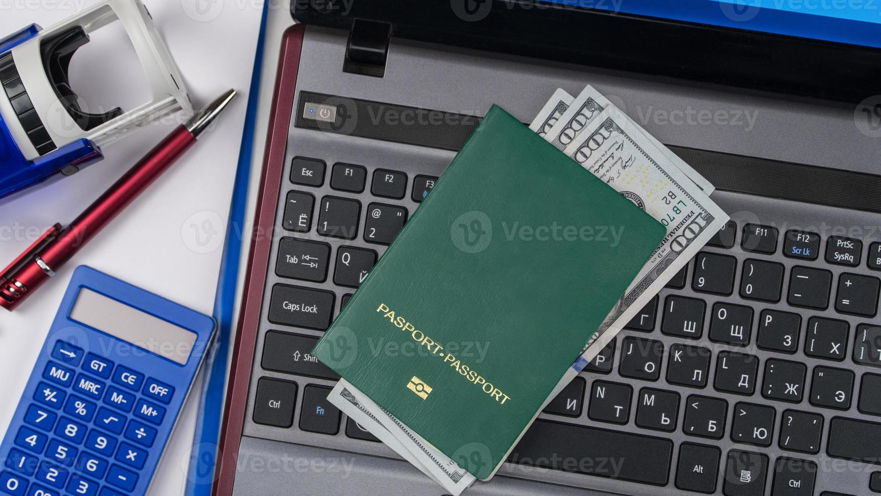 green passport with US dollars on laptop keyboard. Online registration. Concept briber and corruption. Top view photo