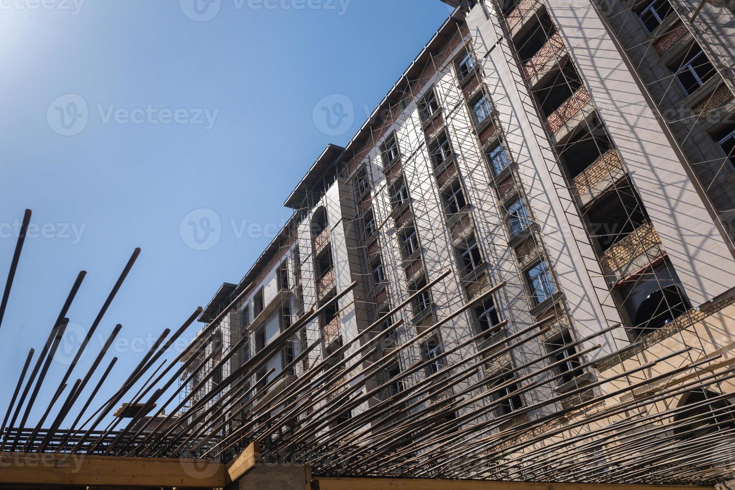 reinforcement bars for concrete pouring on the background of the building under construction. close-up, bottom view photo