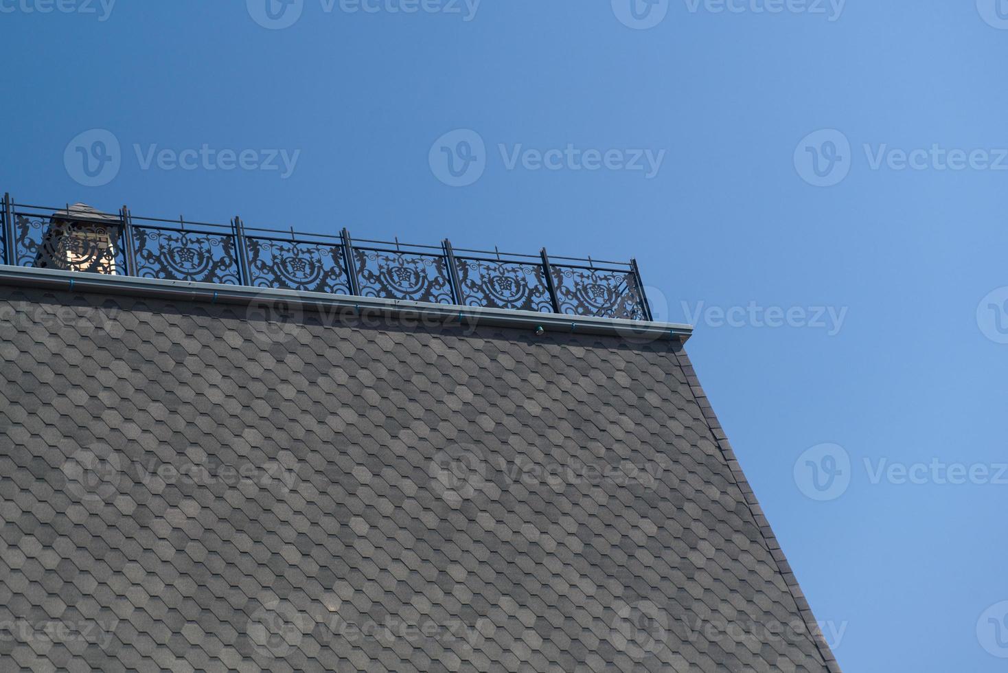 part of the roof with tiles and metal fence photo