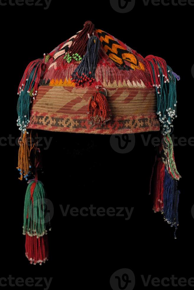 colorful traditional asian skullcap hat with pigtails on a dark background photo