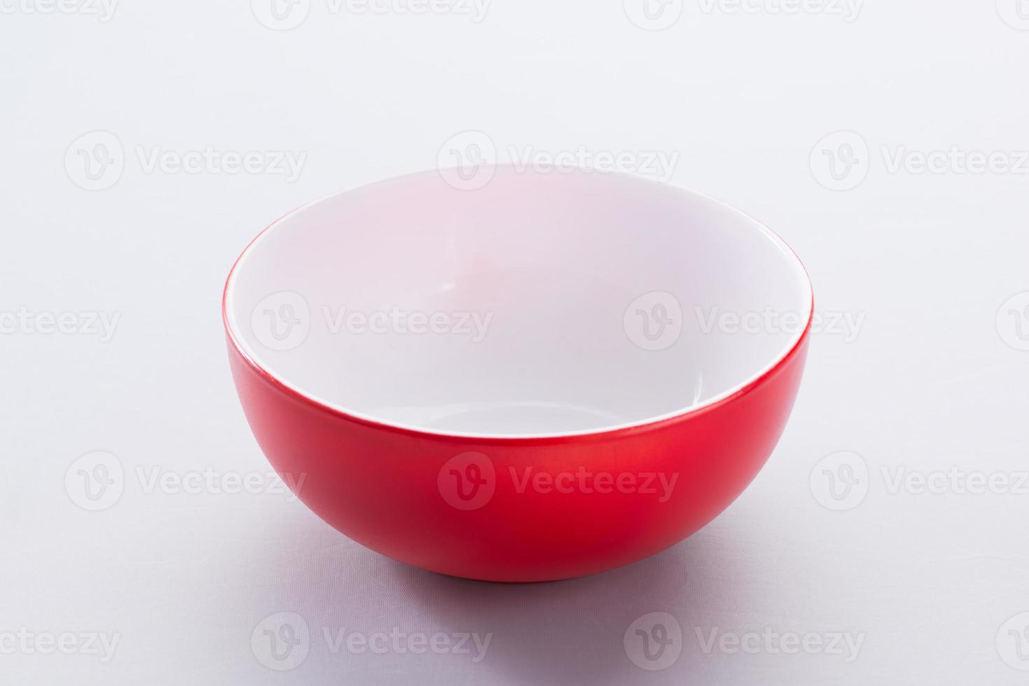 cuenco de cerámica rojo vacío sobre un fondo claro, aislado foto