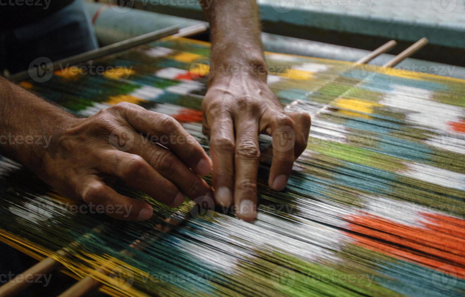 weaving and manufacturing of handmade carpets closeup. man's hands behind a loom photo