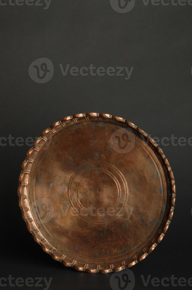 ancient oriental metal tray on dark background. antique bronze tableware photo
