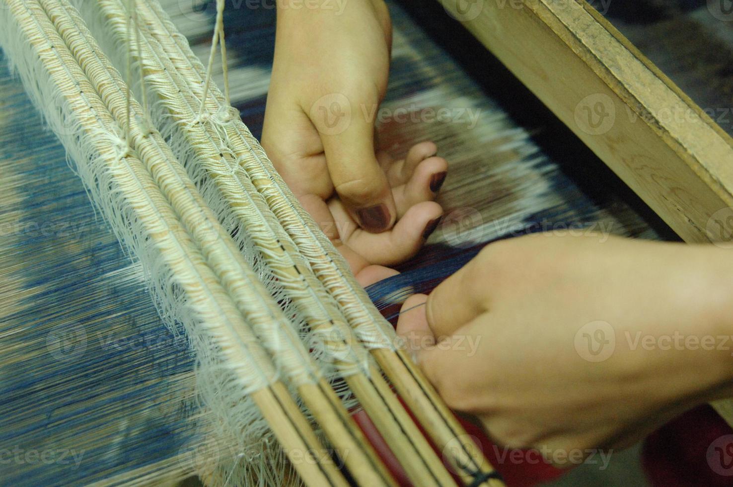 weaving and manufacturing of handmade fabric close up. women's hands behind a loom make cloth photo