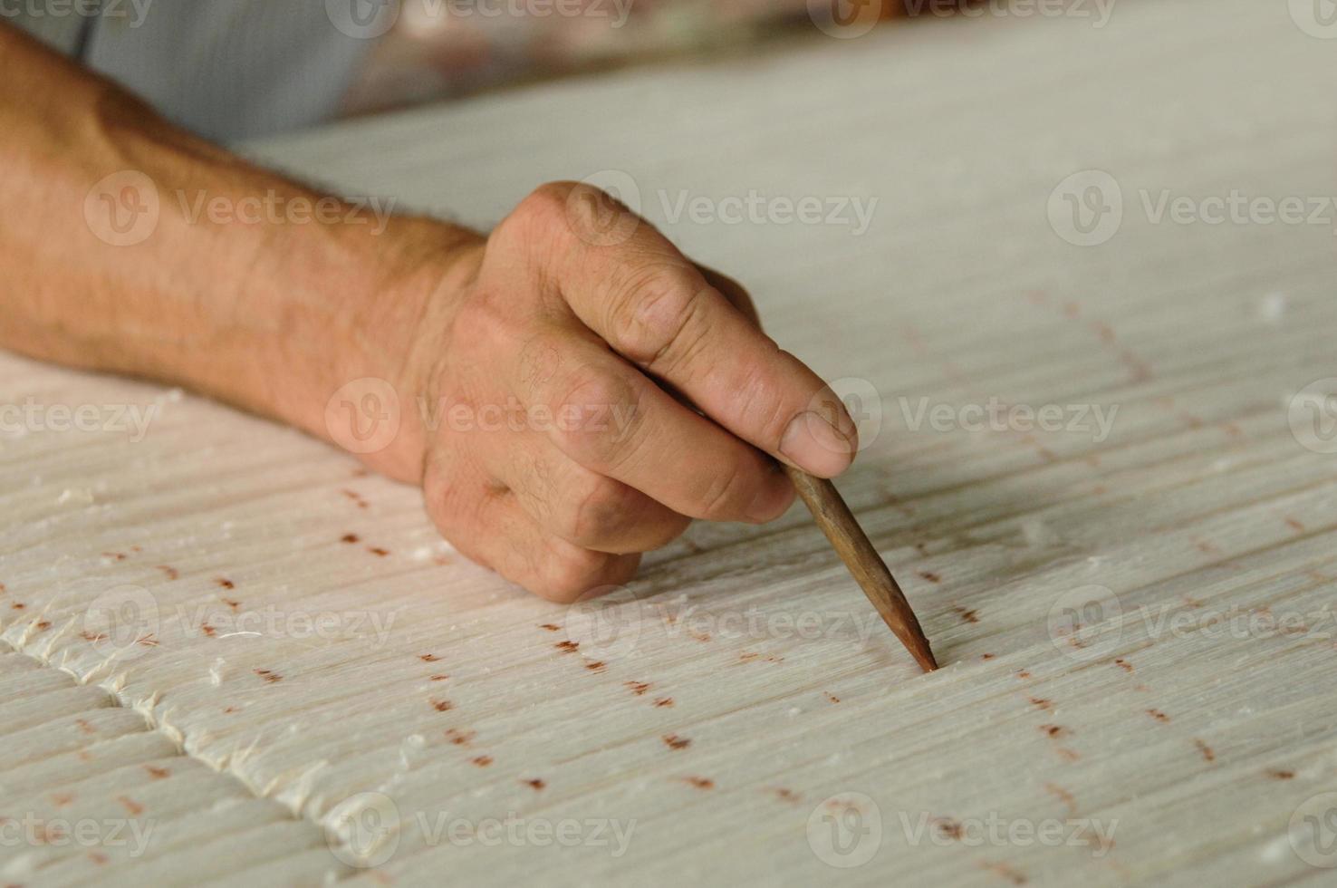 la mano con un lápiz hace marcas en la alfombra. tejido y fabricación de alfombras hechas a mano closeup foto