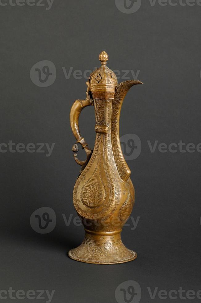 ancient oriental metal teapot on dark background. antique bronze tableware photo