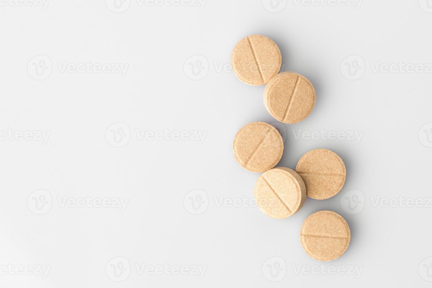 Pile light beige medical tablets on a light background. The view from the top. Isolated photo