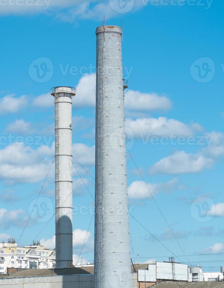 Pipes of an industrial enterprise against a blue sky with clouds. Chimney without smoke photo