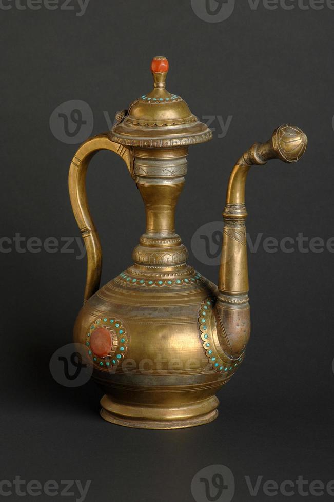 ancient oriental metal teapot on dark background. antique bronze tableware photo