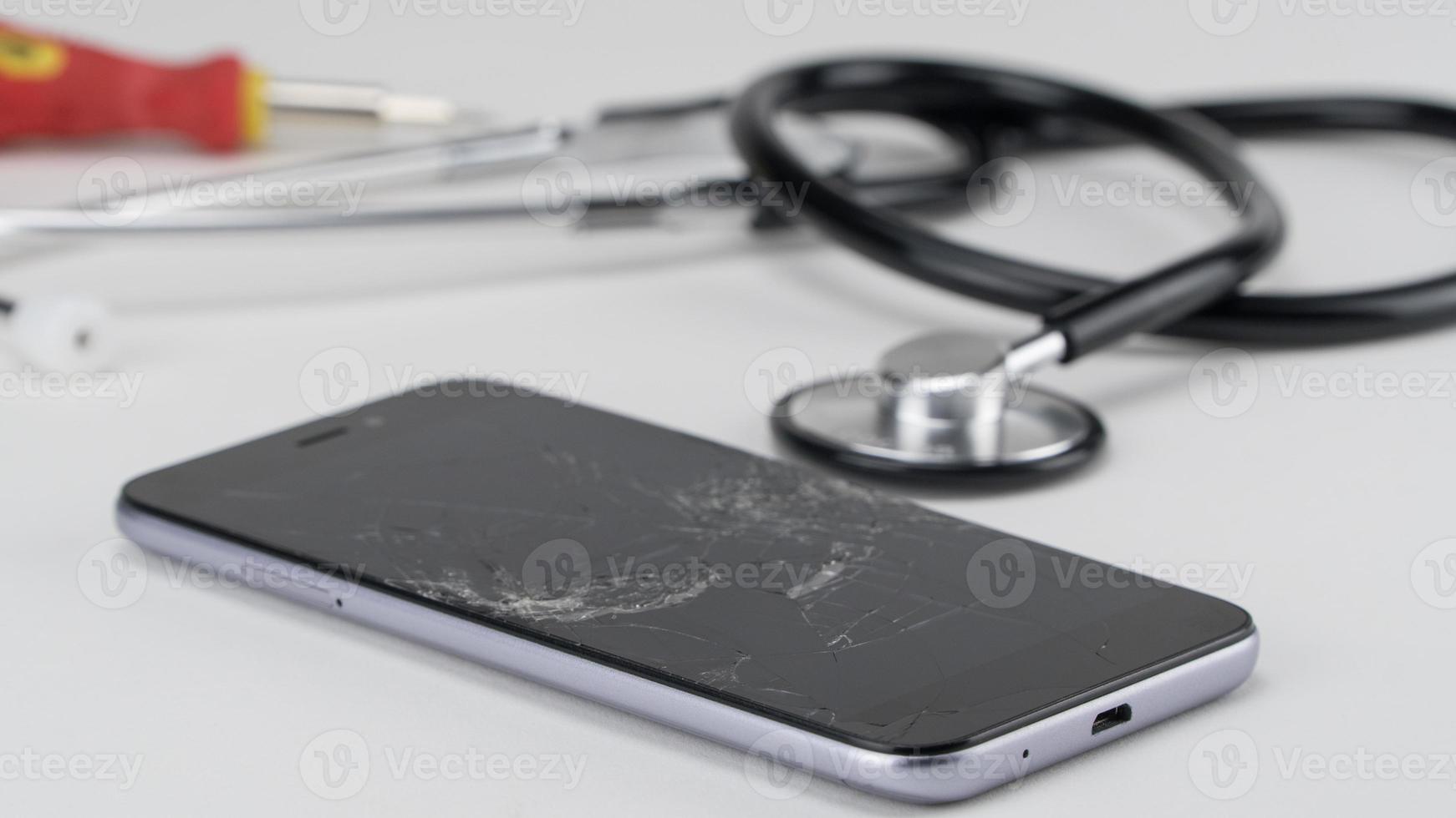 Diagnosing the phone with a stethoscope, near a screwdriver. Phone repair concept photo