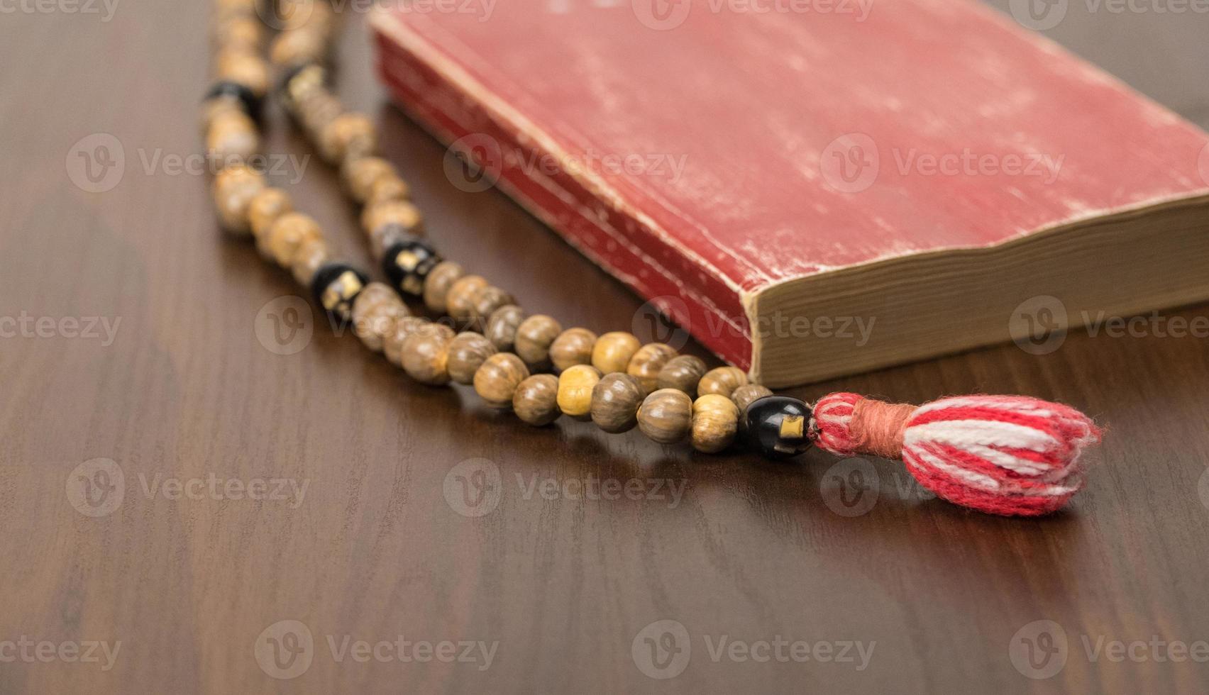 cuentas de oración musulmanas y corán aislados en un fondo de madera. conceptos islámicos y musulmanes foto