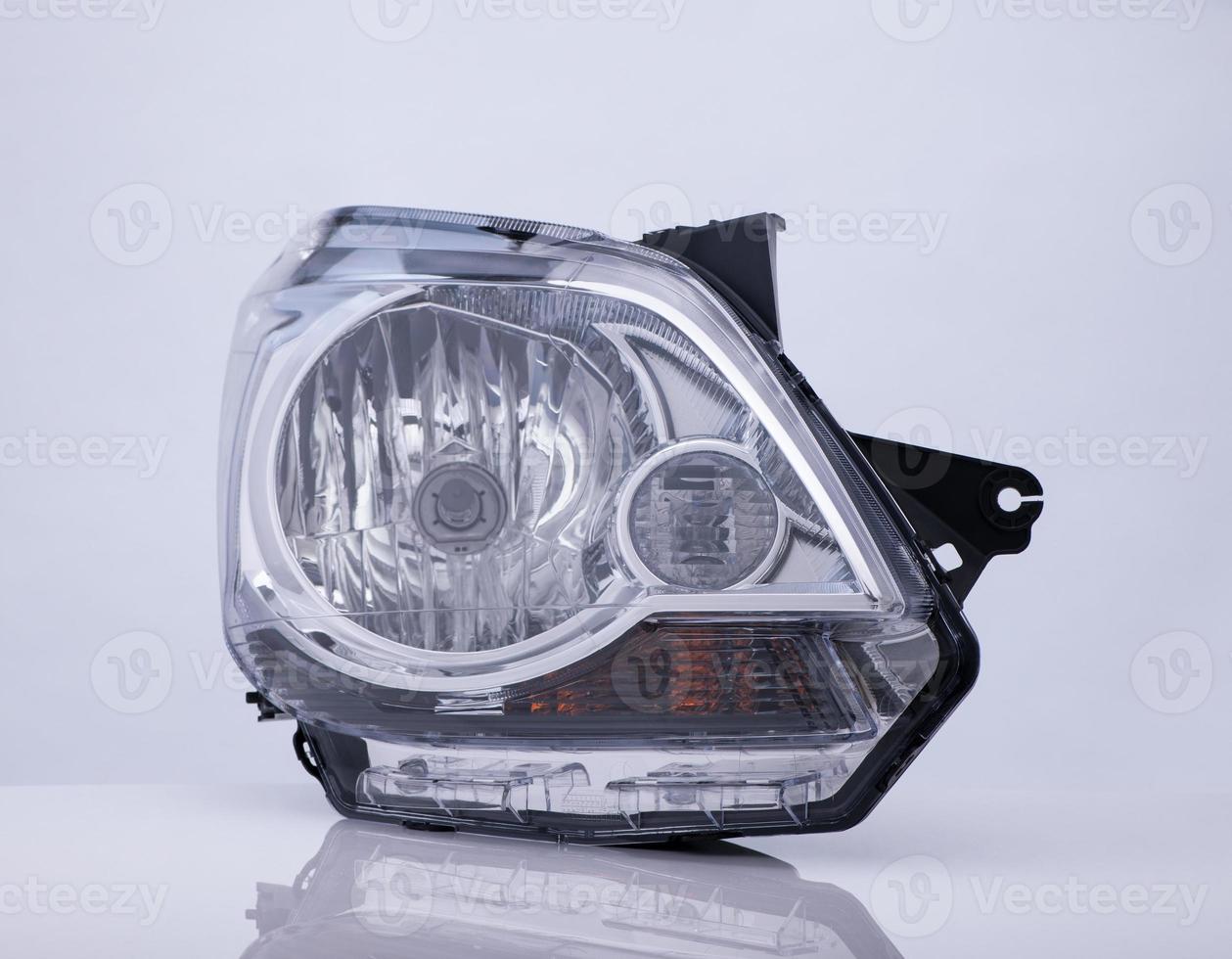 closeup of a car headlight on white background with reflection photo