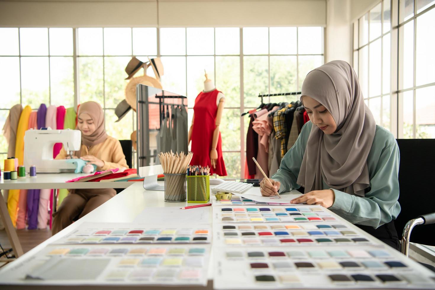 Both Muslim women run a small business in their own homes. Is the design and tailoring of clothes. photo